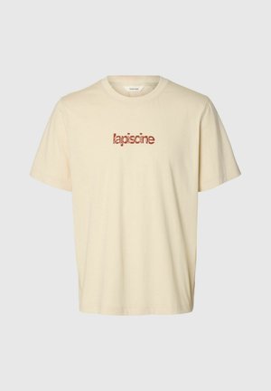 T-shirt beige à manches courtes avec col rond et texte rouge « lapiscine » centré sur la poitrine.