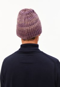 Gebreide beanie in gemêleerde paarse tinten, met een textuurontwerp en een strakke fit. Draag het met een hoge hals, donkerblauwe trui.