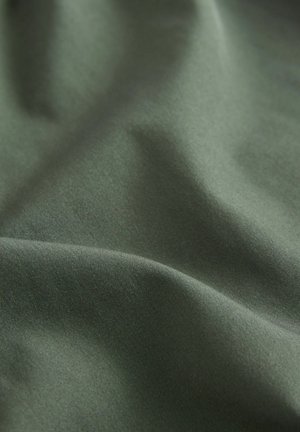 Campionario di tessuto verde scuro, con una texture liscia e una leggera lucentezza, che presenta pieghe morbide e sottili variazioni di colore e luce.