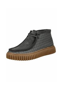Chaussures montantes en daim gris avec une semelle en caoutchouc, présentant un motif pied-de-poule texturé et des coutures contrastées. Détail discret de laçage.