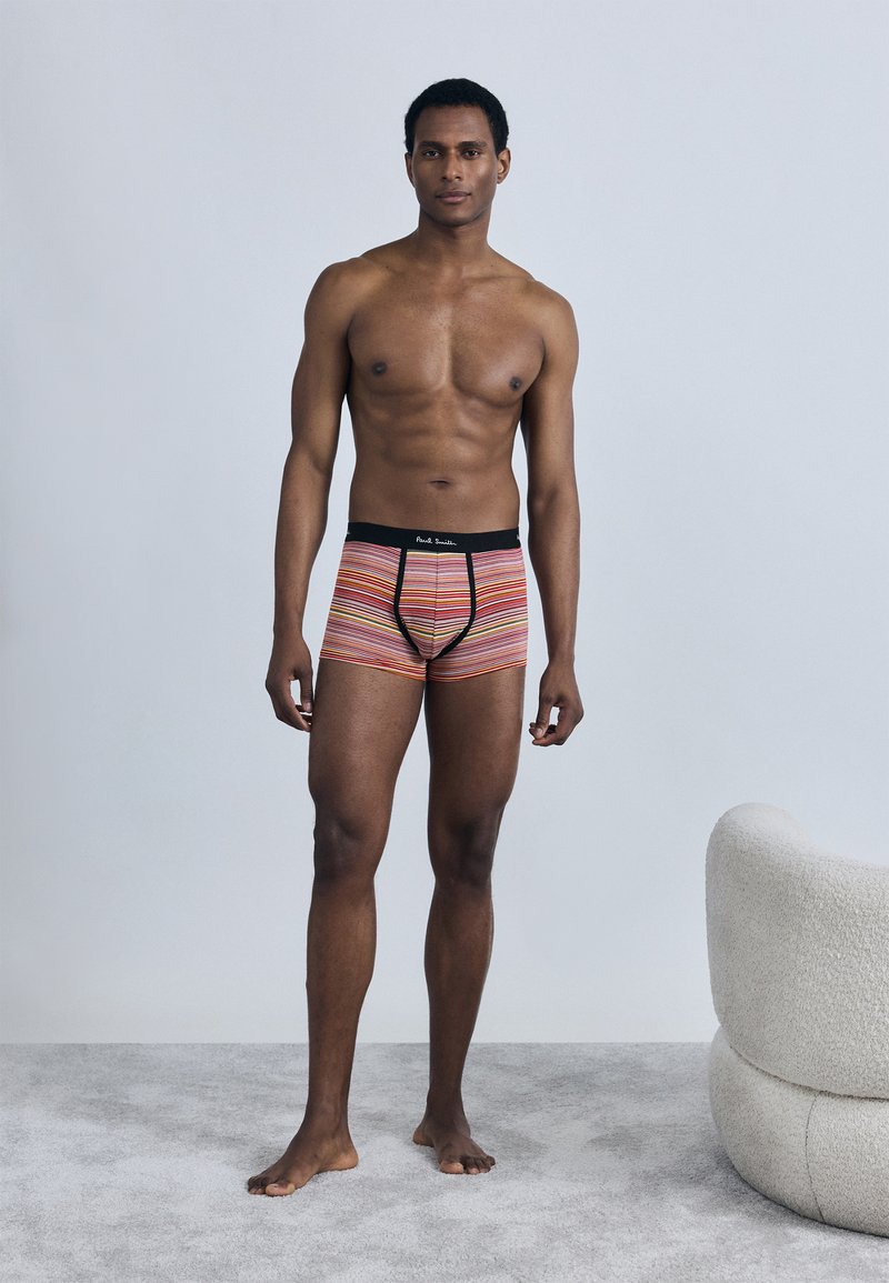 Πολύχρωμα ριγέ μποξεράκια με μαύρη μέση που φέρε ι λογότυπο. Το ύφασμα είναι λείο με εφαρμοστή σχεδίαση, παρουσιάζεται σε όρθιο μοντέλο.