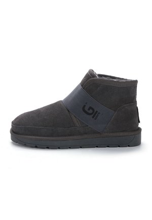 Knöchelhohe Stiefel aus dunkelgrauem Wildleder mit einem grauen elastischen Band, das ein Logo trägt. Flaue Gummisohle mit strukturiertem Grip. Weiche Innenauskleidung.