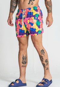 Shorts de bain colorés avec un motif d'oursons en gomme en rose, violet, vert et jaune. Fabriqués en tissu léger avec une taille élastique.