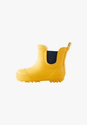 Gele rubberen regenlaars met een stevige zool, zwarte textielaccenten en een witte bontvoering aan de bovenkant. Voorzien van een lus voor gemakkelijk aantrekken.