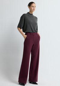 Szary, krótki rękaw, dzianinowy top połączony z wysokim stanem, szerokimi nogawkami bordowych spodni. Gładki materiał o strukturalnym kroju i bocznymi kieszeniami.