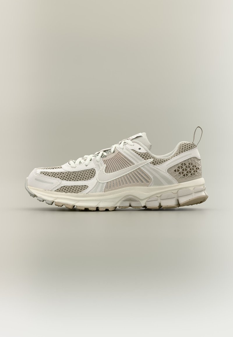 Baskets de sport en maille blanche et beige avec semelle texturée, fermeture à lacets et languette à l'arrière, vues de profil.