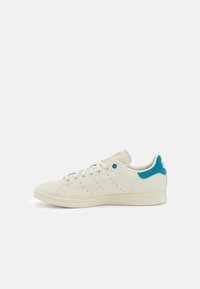 Witte leren sneakers met een teal suède accent bij de hak. Voorzien van geperforeerde details aan de zijkant en platte witte veters. Klassiek ontwerp.