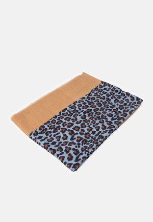 Écharpe pliée avec une section unie beige et un motif léopard sur fond bleu, posée sur une surface blanche.