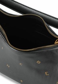 Borsa a tracolla in pelle nera con cerniera dorata e lettere in rilievo. Presenta una consistenza liscia e un ampio interno con slot per carte.