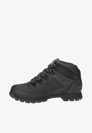 Zapatilla deportiva de caña alta en color negro que cuenta con un upper texturizado, cordones resistentes, suela de goma con tracción y talón reforzado para soporte.