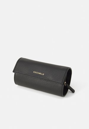 Black leather cylindrical pouch with a textured surface, featuring a gold logo and zipper detail, designed for compact storage.