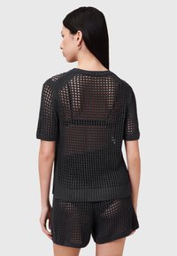 Sort strikket sweater med korte ærmer, der har et åbent maskedesign og ribbestrikket kant ved halsen og ærmerne, parret med matchende shorts.