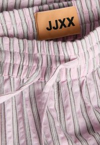 Κοντινό πλάνο ροζ και λευκής ριγωτής υφασμάτινης με κορδόνι και ραμμένη μπεζ ετικέτα που γράφει «JJXX.»