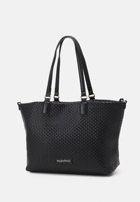 Black woven tote bag with two shoulder straps. Features a textured exterior and a gold logo plaque at the base. Measures medium size.