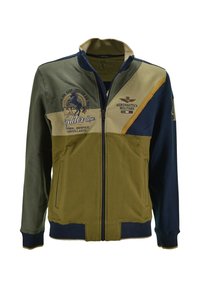 Giacca in pile in verde oliva, blu navy e crema. Presenta una chiusura a zip, tasche laterali e loghi ricamati sul davanti.