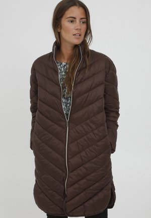Brun, quilted pufferjakke med diagonal syning, høj krave, frontlynlås og blød tekstur, båret over en mønstret skjorte.