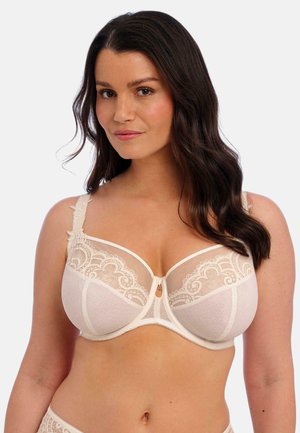 Cream lace bra with sheer panels, intricate floral embroidery, underwire support, and a small decorative center detail. Soft, textured fabric.
