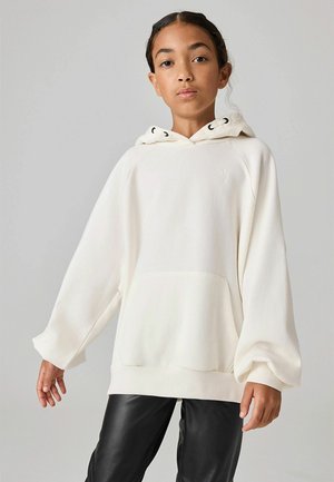 Hoodie oversize blanc en tissu doux, avec une poche kangourou, une capuche avec cordon de serrage et des poignets côtelés. Assorti à un pantalon en cuir noir.