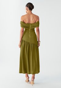 Olivgrünes, schulterfreies Maxikleid aus strukturiertem Stoff, tailliertem Oberteil, Reißverschluss auf der Rückseite und gestuftem Rock. Einfaches Design mit einer glatten Oberfläche.