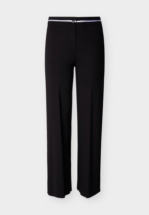 Zwarte broek met rechte pijpen, voorzien van een witte horizontale streep aan de tailleband en een knoopsluiting aan de voorkant.