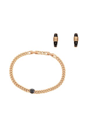 Bransoletka z łańcuszka ze złotem i czarnym kamieniem oraz dopasowane złote kolczyki koła z czarnymi elementami na białym tle.