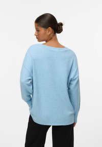 Pull oversized bleu clair avec un grand col et des épaules tombantes. Sa texture douce, ses poignets côtelés et ses détails à l'ourlet procurent une coupe décontractée.