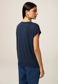 Top blu navy a maniche corte con una vestibilità rilassata, in tessuto morbido e scollatura rotonda, abbinato a jeans blu testurizzati.