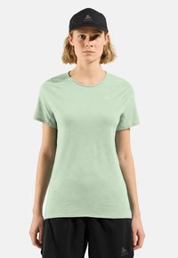 Light green short-sleeve athletic t-shirt with a round neck and a textured finish, paired with a black cap featuring a logo.
