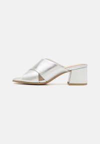 Mules en cuir argenté à talon bloc avec un design croisé, bout ouvert, finition texturée et un talon carré robuste.