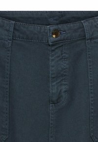 Donkerblauwe denimspijkerbroek met knoopsluiting, voorzakken en contrasterende stiksels. Materiaal lijkt duurzaam met een gladde textuur.