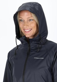 Navy waterproof jacket with a zippered front, attached hood, and drawstring closure. Features logo "SWEMOUNT" on the chest. Smooth texture.