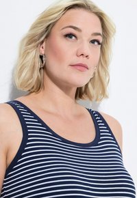 Top in cotone a righe navy e bianche con una texture a costine. Spalline larghe e scollatura arrotondata. Lo sfondo è bianco uniforme.