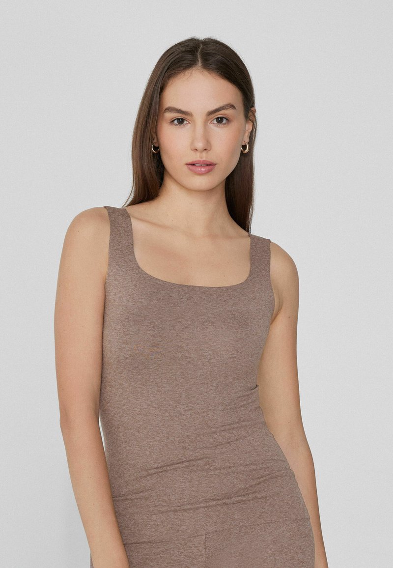Débardeur en coton brun avec une encolure carrée, des bretelles larges et une coupe ajustée. Texture lisse sans motifs visibles ni éléments métalliques.