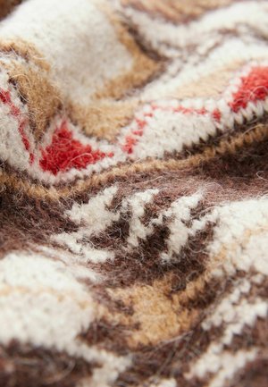 Braun- und beige gestrickter Stoff mit weißen und roten geometrischen Mustern, der eine weiche, strukturierte Oberfläche und ein warmes, gemütliches Aussehen zeigt.
