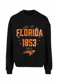 Fekete pulóver, amelyen az "University of Florida" és az "1853" narancssárga és ezüst betűkkel szerepel, az ujján logó designnal.