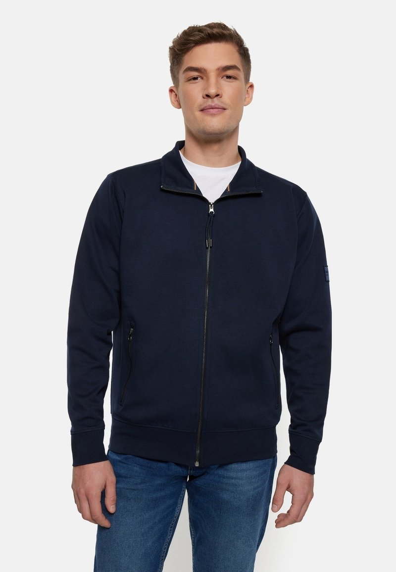Navy Zip-Up-Sweatshirt aus weichem Stoff, mit hohem Kragen, seitlichen Taschen, gerippten Bündchen und einem sauberen, minimalen Design.