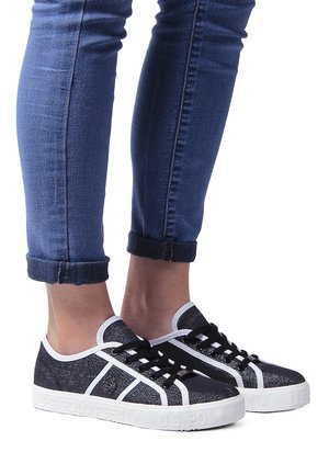 Black sneakers with white accents, a textured upper, and lace closure. They feature a rounded toe and a white rubber sole.