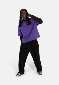 Lilla crop-top laget av bomull, med en avslappet passform. Kombinert med svarte løse joggebukser med et enkelt design.