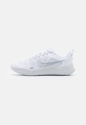 Baskets de sport blanches avec une tige en maille, des rayures texturées et une semelle rembourrée. Présentent un logo discret sur le côté et une languette au niveau du talon.