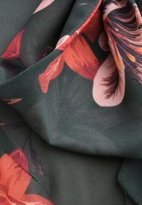 Materiał w kwiatowy wzór z intensywnymi pomarańczowymi i różowymi kwiatami na ciemnozielonym tle, o miękkiej, lekkiej teksturze i zwiewnym spadzie.