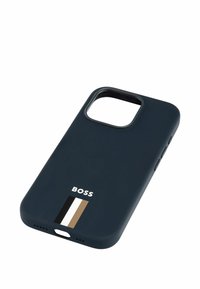 Tmavě modrý silikonový obal na telefon s výřezem pro kameru, zdobený bílým logem a vertikálním akcentovým pruhom v krémové, černé a hnědé.