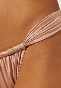 Rosa Satin-Bikiniunterteil mit einem gerafften Seitenknotendesign und glatter Oberflächenstruktur, das eine minimalistische Ästhetik betont.