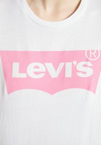 White cotton t-shirt featuring a large pink Levi's logo with a distinctive arch design. The neckline is round and ribbed.