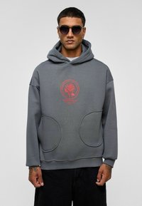Grijze hoodie met een grote voorzak, een capuchon met trekkoord en een rode roosgrafiek op de borst. Heeft een ontspannen pasvorm en een zachte textuur.