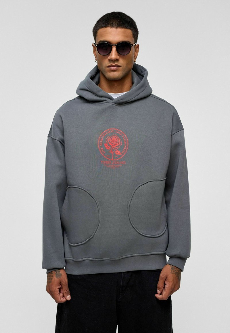 Grijze hoodie met een grote voorzak, een capuchon met trekkoord en een rode roosgrafiek op de borst. Heeft een ontspannen pasvorm en een zachte textuur.