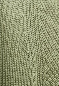 Groen gebreid stof met een gestructureerd, geribd patroon met duidelijke rijen. Het materiaal lijkt zacht, met een lichte glans.