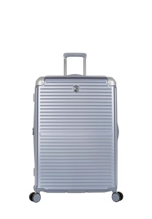 Valise rigide argentée avec des rainures horizontales, quatre roues et une poignée télescopique étendue sur fond blanc.