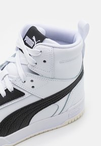Witte leren high-top sneakers met zwarte accenten en een mesh voering. Voorzien van een gestructureerde zwarte lijn en een opvallend merklogo.