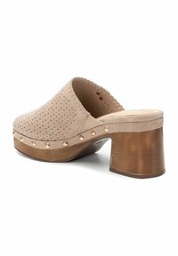 Zoccoli in suede beige con design perforato e rivetti in metallo dorato ai lati; tacco in legno con finitura testurizzata.