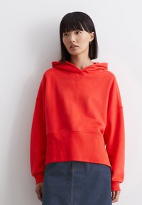 Rode hoodie met een comfortabele pasvorm, ribbelachtige boorden en lange mouwen. Gepaarde met een donkerdenim rok, met een klassieke snit.